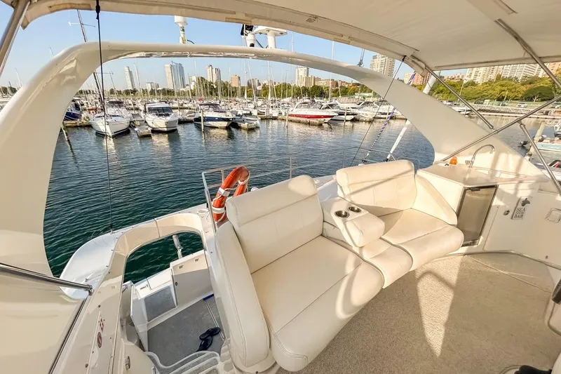 Slide: The Image of 2003 Silverton 410 Sport Bridge yacht interior with marina view, featuring white seating and sea bar. - 114
