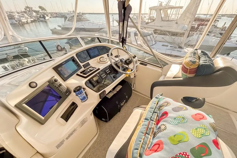 Slide: The Image of 2003 Silverton 410 Sport Bridge helm with modern controls, marina view, and colorful cushions. - 115