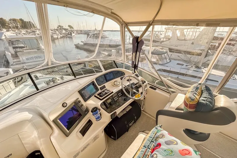 Slide: The Image of 2003 Silverton 410 Sport Bridge helm with marina view, featuring modern navigation equipment. - 117