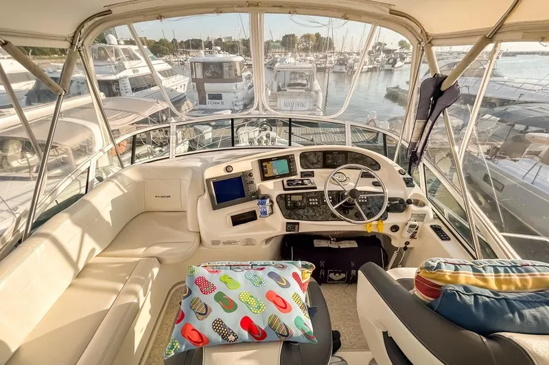 Slide: The Image of 2003 Silverton 410 Sport Bridge yacht interior with helm, colorful cushions, and marina view. - 120