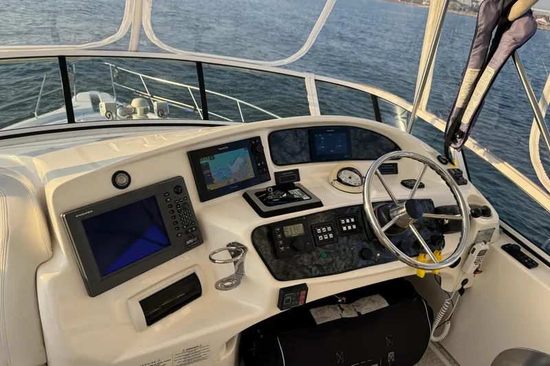 Slide: The Image of 2003 Silverton 410 Sport Bridge helm with navigation equipment and steering wheel, overlooking the water. - 122