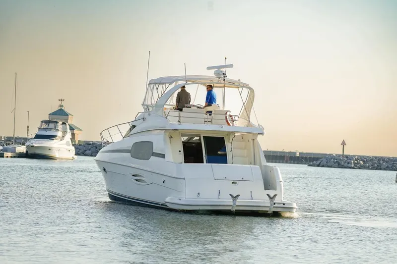 Slide: The Image of 2003 Silverton 410 Sport Bridge yacht cruising in a serene marina at sunset. - 17