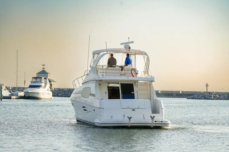 Slide: The Image of 2003 Silverton 410 Sport Bridge yacht cruising in a serene marina at sunset. - 18