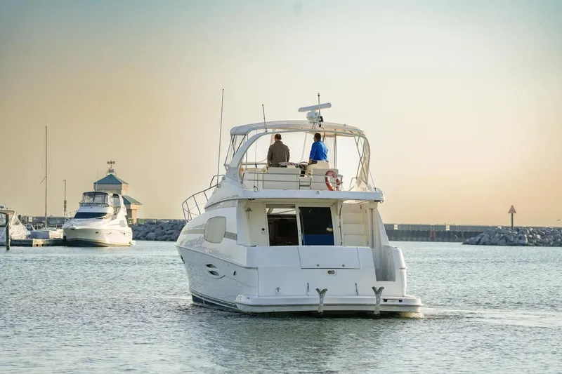 Slide: The Image of 2003 Silverton 410 Sport Bridge yacht cruising in a serene marina at sunset. - 19