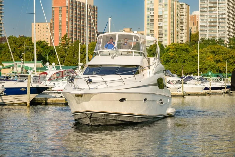 Slide: The Image of 2003 Silverton 410 Sport Bridge yacht docked in a marina with cityscape background. - 6