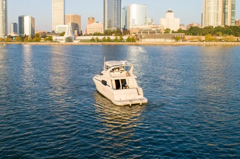 Slide: The Image of 2003 Silverton 410 Sport Bridge yacht cruising near city skyline on a sunny day. - 68