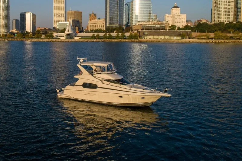 Slide: The Image of 2003 Silverton 410 Sport Bridge yacht on calm water with city skyline backdrop. - 78