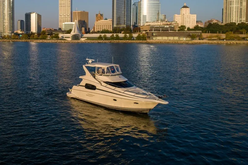 Slide: The Image of 2003 Silverton 410 Sport Bridge yacht on calm water with city skyline backdrop. - 81