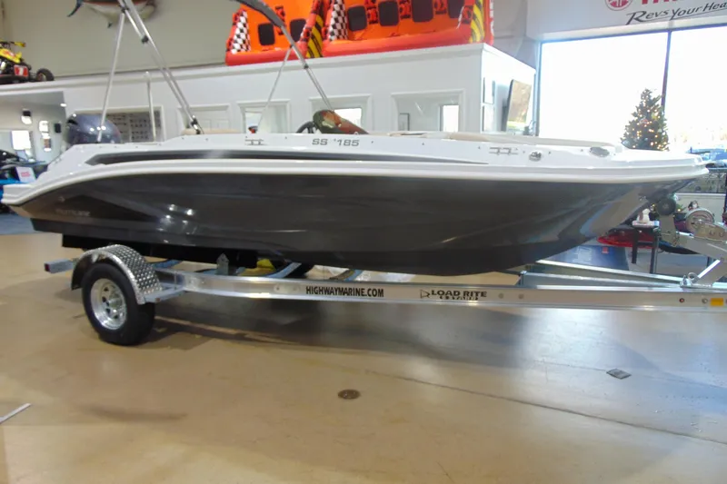 The Image of 2026 Hurricane SunDeck Sport 185 OB boat on trailer in showroom. - 1