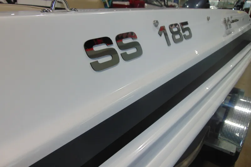Slide: The Image of 2026 Hurricane SunDeck Sport 185 OB boat, close-up of SS 185 emblem on white hull. - 16