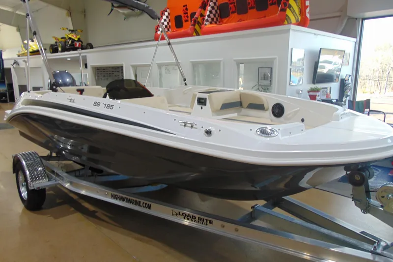 Slide: The Image of 2026 Hurricane SunDeck Sport 185 OB boat displayed indoors on a trailer. - 2