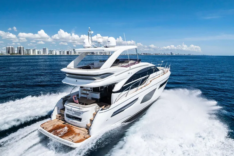 Slide: The Image of Luxurious 2022 Princess 55 Flybridge yacht cruising on open sea with city skyline backdrop. - 101