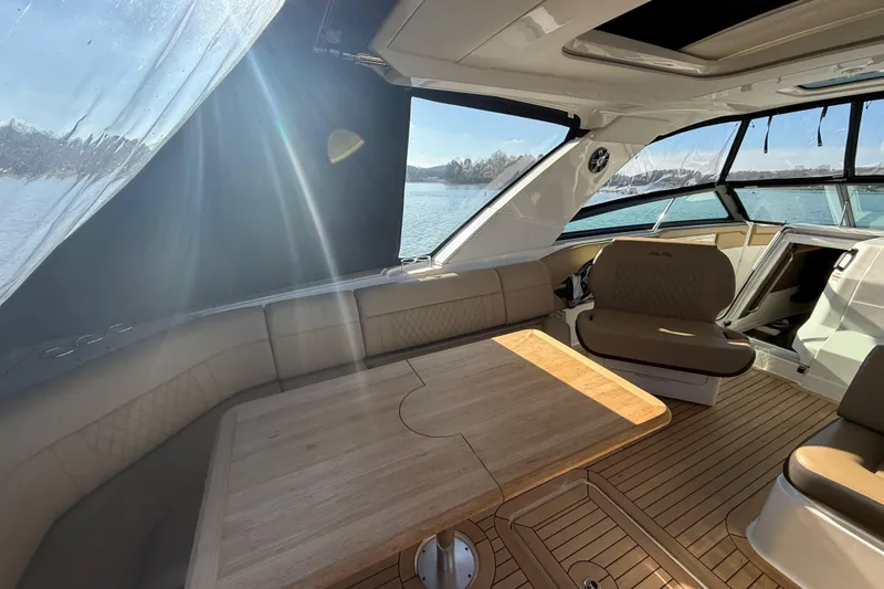 Slide: The Image of Interior of 2022 Sea Ray SLX 400 yacht with sunlit seating and wooden table. - 37