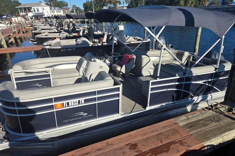 Slide: The Image of 2023 Bennington 22SSR pontoon boat docked, featuring spacious seating and canopy. - 7