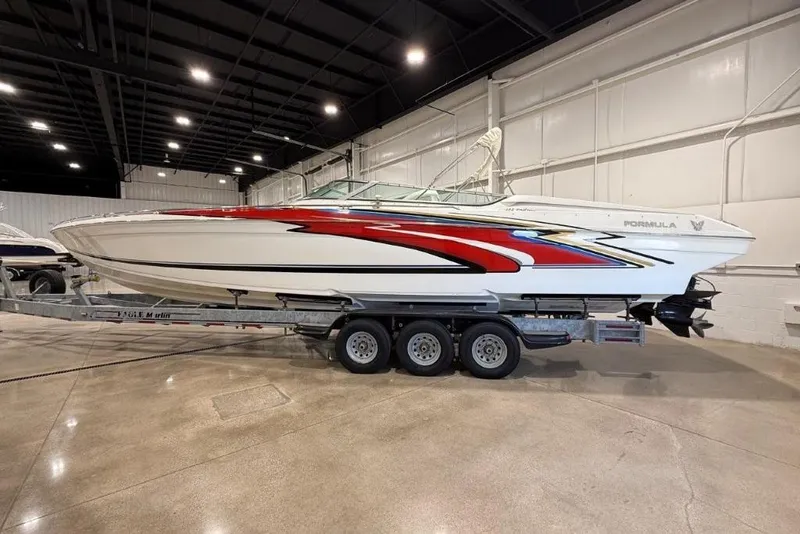 Slide: The Image of 1998 Formula 382 FASTech boat with vibrant red and blue graphics on a trailer in a warehouse. - 3