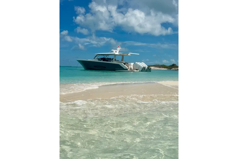 Slide: The Image of 2026 Regal 50 SAV yacht anchored near a sandy beach under a clear blue sky. - 28