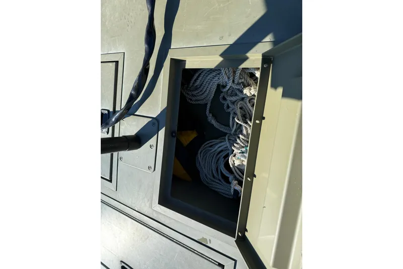 Slide: The Image of Open storage compartment on 2014 Lowe Roughneck 1650 DLX boat with coiled rope inside. - 11