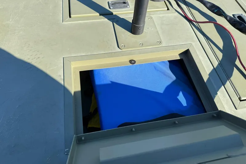 Slide: The Image of Open storage compartment on 2014 Lowe Roughneck 1650 DLX boat, revealing blue interior. - 15
