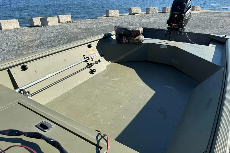 Slide: The Image of 2014 Lowe Roughneck 1650 DLX boat interior with motor, near water. - 16