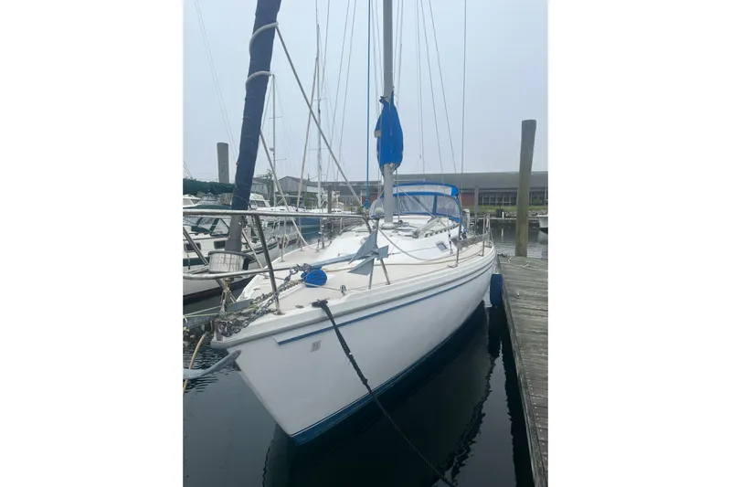 Slide: The Image of 1985 Catalina 36 sailboat docked at marina, featuring white hull and blue accents. - 18