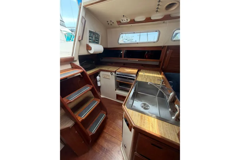 Slide: The Image of Interior of 1985 Catalina 36 sailboat featuring kitchen area with sink and wooden cabinetry. - 29