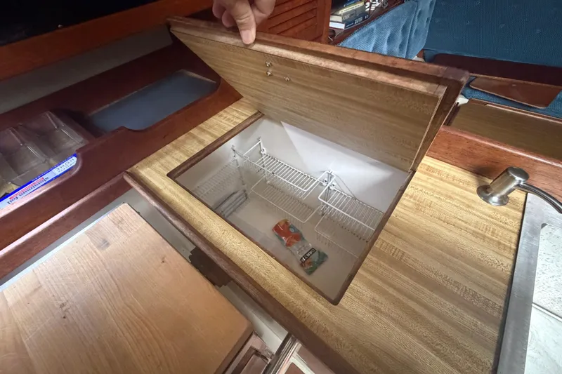 Slide: The Image of Open storage compartment in 1985 Catalina 36 yacht kitchen with wooden finish. - 33