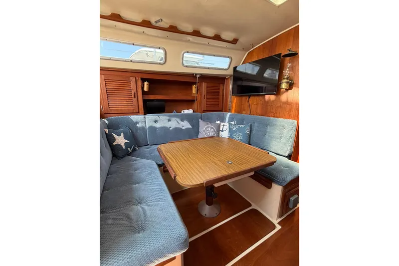 Slide: The Image of Interior of a 1985 Catalina 36 sailboat with blue cushioned seating and wooden table. - 35