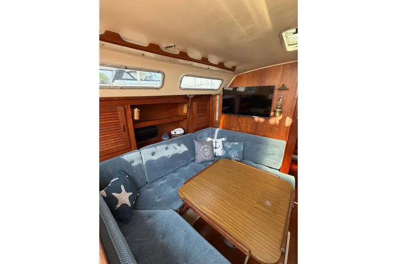 Slide: The Image of Cozy interior of 1985 Catalina 36 sailboat with blue seating and wooden table. - 36