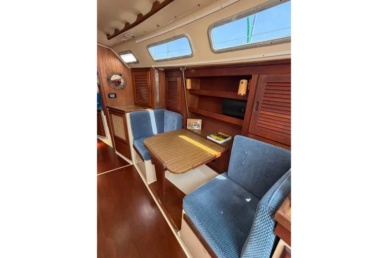 Slide: The Image of Interior of 1985 Catalina 36 sailboat with wooden table and blue upholstered seating. - 37