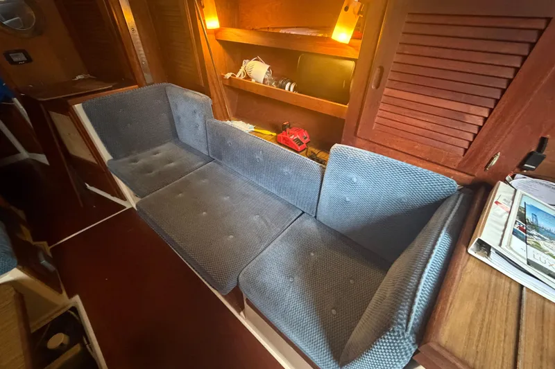 Slide: The Image of Interior of 1985 Catalina 36 sailboat with blue cushioned seating and wooden cabinetry. - 38