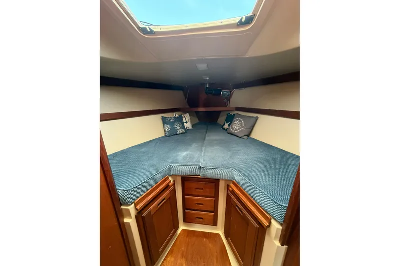 Slide: The Image of 1985 Catalina 36 sailboat cabin with blue cushions and nautical-themed pillows. - 42
