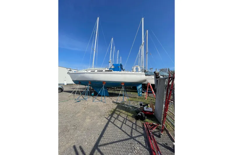 Slide: The Image of 1985 Catalina 36 sailboat on stands in a boatyard under clear blue sky. - 44