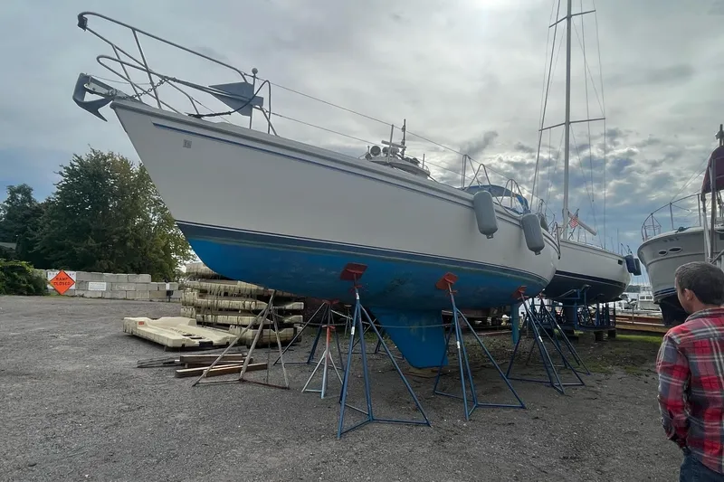 Slide: The Image of 1985 Catalina 36 sailboat on stands in a boatyard under cloudy sky. - 46