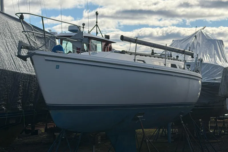 Slide: The Image of 1985 Catalina 36 sailboat on stands, partially covered, under a cloudy sky. - 48