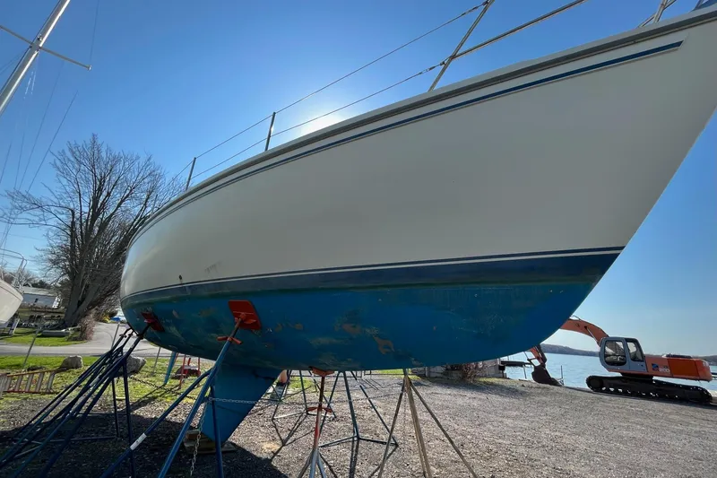 Slide: The Image of 1985 Catalina 36 sailboat on stands, blue hull, sunny day, construction equipment nearby. - 50