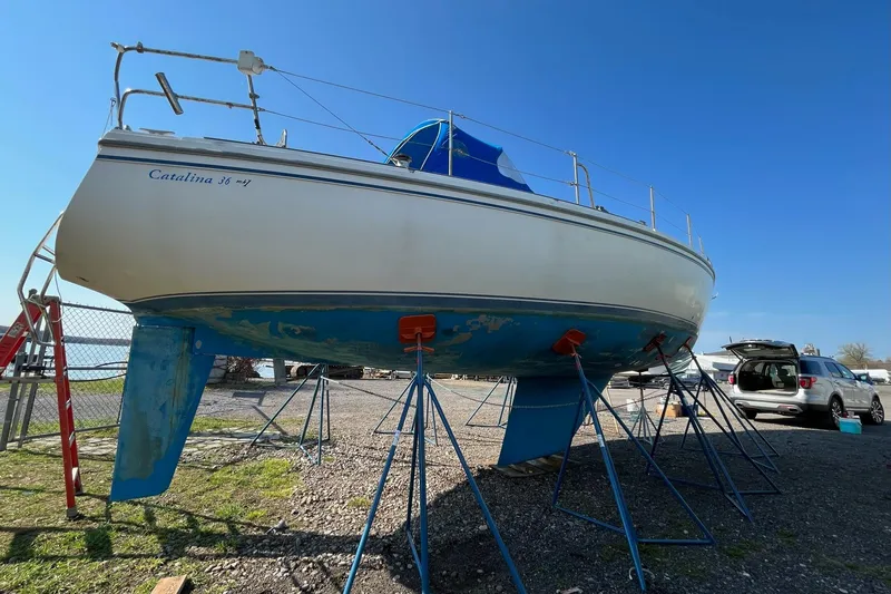 Slide: The Image of 1985 Catalina 36 sailboat on stands in a boatyard under clear blue sky. - 51