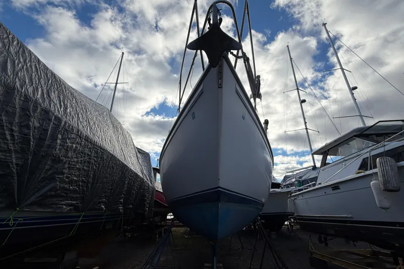 Slide: The Image of 1985 Catalina 36 sailboat in dry dock, surrounded by other boats under a cloudy sky. - 55