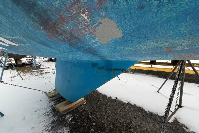 Slide: The Image of Bottom view of a 1985 Catalina 36 sailboat hull on stands, showing wear and paint chipping. - 57