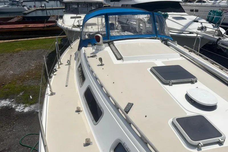 Slide: The Image of 1985 Catalina 36 sailboat docked, featuring a spacious deck and blue canopy. - 63