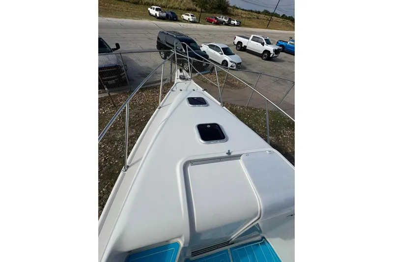 Slide: The Image of 1996 Pro-Line 3400 Cuddy boat deck view with parked cars in the background. - 20