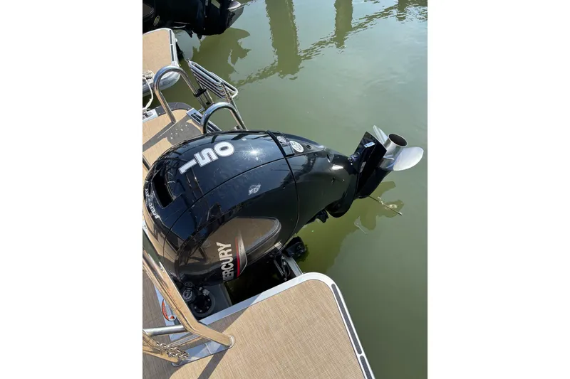 Slide: The Image of Outboard motor on 2024 Harris HCX23 boat, docked on calm water. - 10