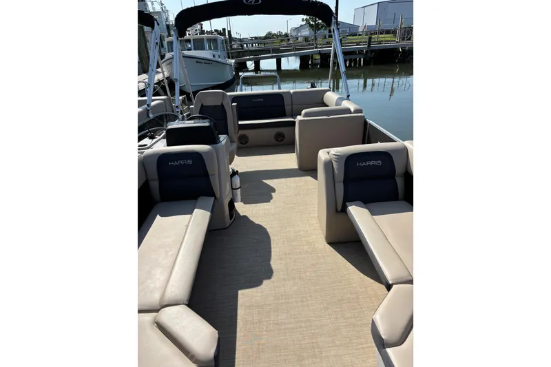 Slide: The Image of 2024 Harris HCX23 pontoon boat interior with beige seating and waterfront view. - 3