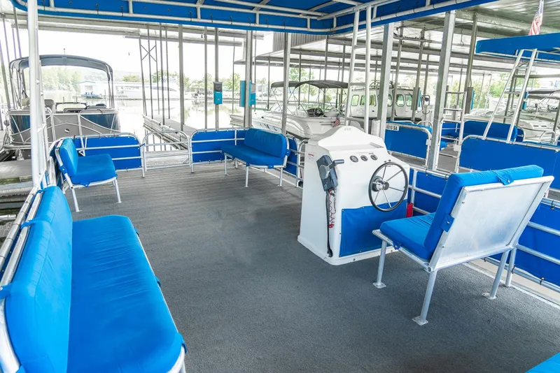 Slide: The Image of Pontoon boat interior with blue seating, steering console, and canopy, part of a rental fleet. - 26
