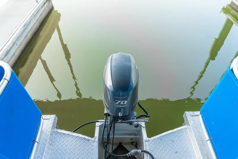 Slide: The Image of Outboard motor on a 2000 Custom Pontoon Rental Fleet boat, docked on calm water. - 31