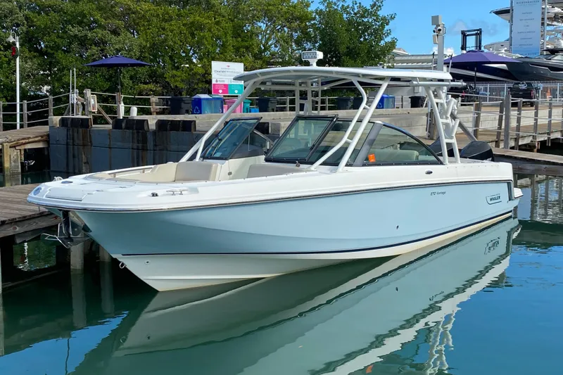 Slide: The Image of 2019 Boston Whaler 270 Vantage boat docked in a marina, reflecting on calm water. - 12