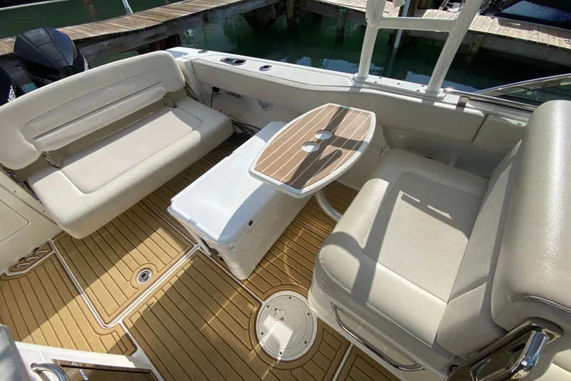 Slide: The Image of 2019 Boston Whaler 270 Vantage interior with seating and table, docked by water. - 34