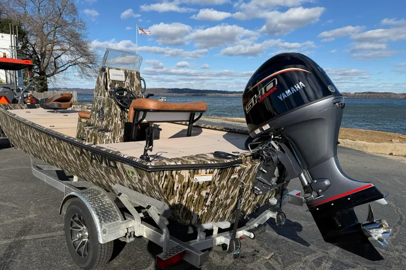 Slide: The Image of 2026 Avid 20 ROGUE CC boat with Yamaha engine, camo design, parked by a lake. - 3