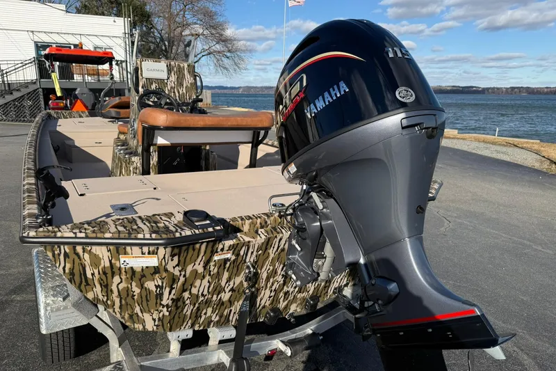 Slide: The Image of 2026 Avid 20 ROGUE CC boat with Yamaha outboard motor, camo design, docked by the water. - 4