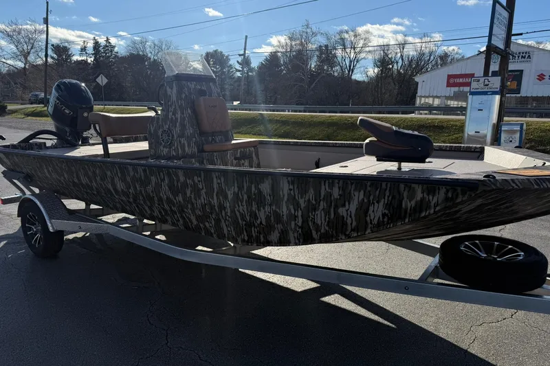 Slide: The Image of 2026 Avid 20 ROGUE CC boat on trailer, camo design, parked outdoors. - 7