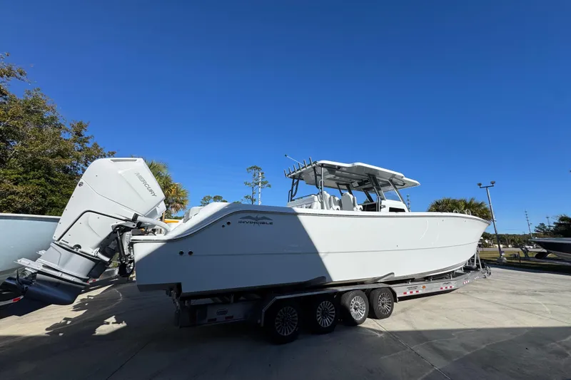 Slide: The Image of 2026 Invincible 46 Catamaran on trailer under clear blue sky. - 13
